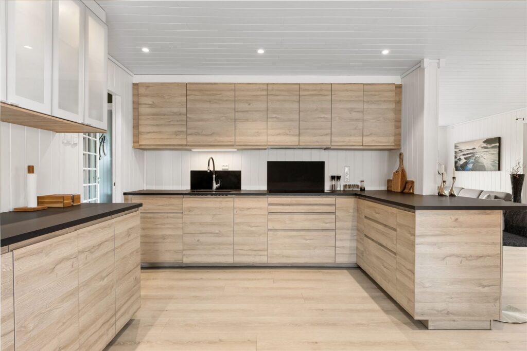 A modern kitchen with light wood cabinets and black counters