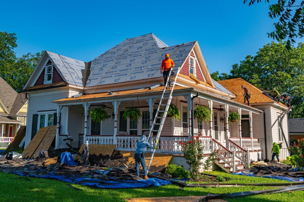 A crew working on the porch and roof of a two-story house